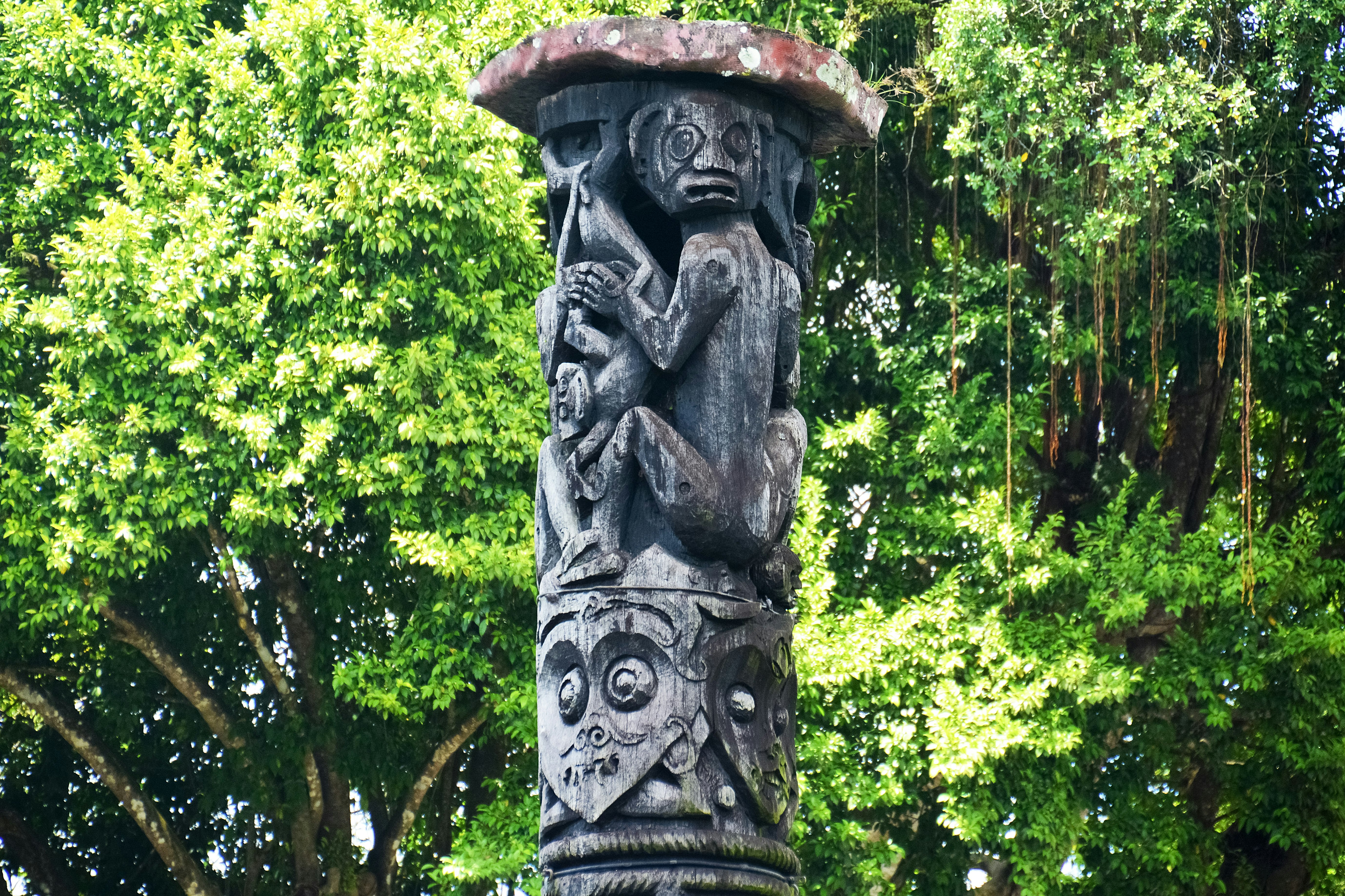 brown wooden statue near green trees during daytime